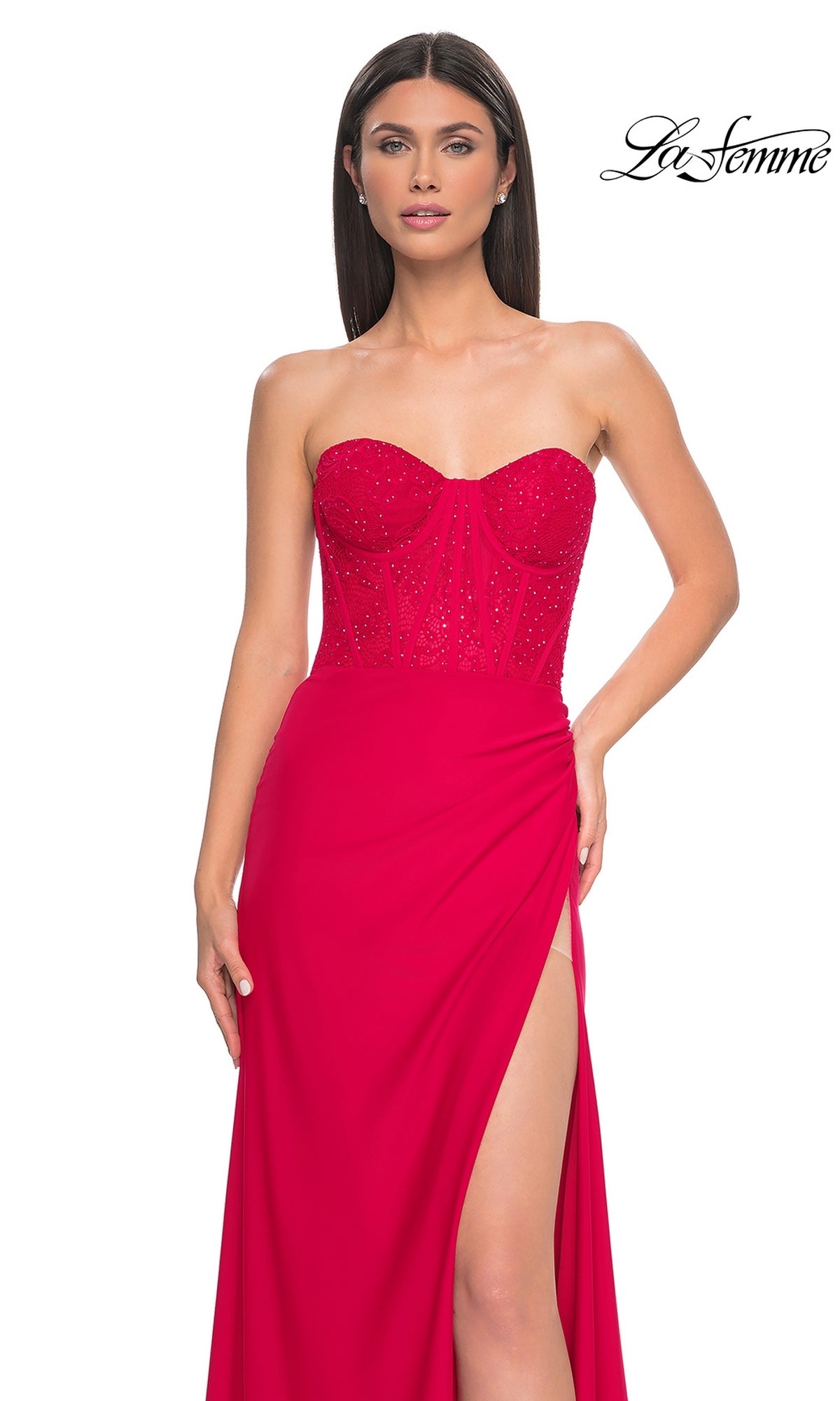 A woman models the La Femme Strapless Long Corset Prom Dress 32234 featuring a sparkly embellished corset and high slit, posing against a white background with the